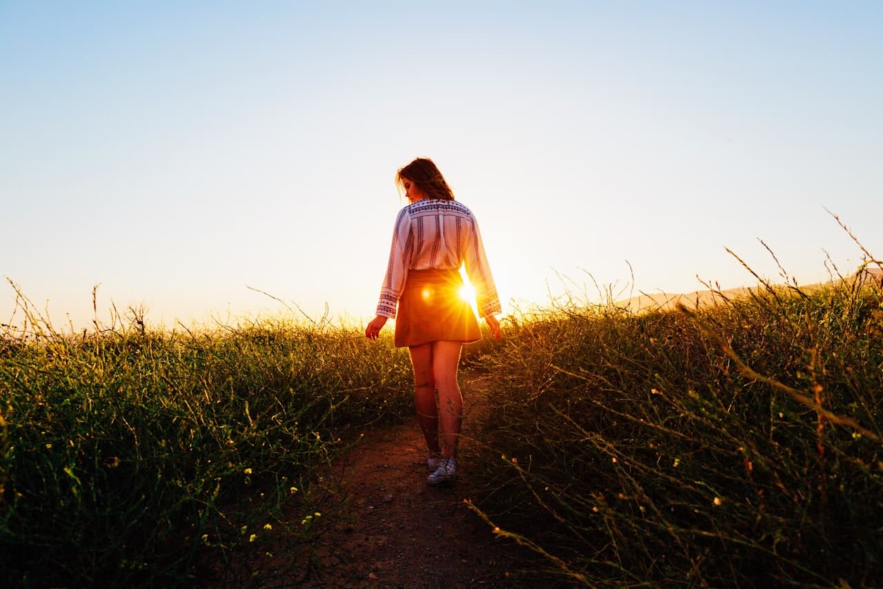 A person walking outdoors on a quiet path at golden hour